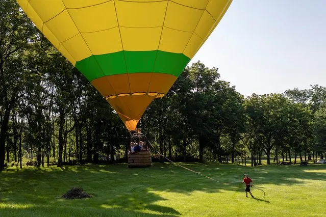 A hot air balloon prepares to land in a residential area during the New Jersey Lottery Festival of Ballooning in Flemington, New Jersey, U.S., July 24, 2021. (Photo by Hannah Beier/Reuters)