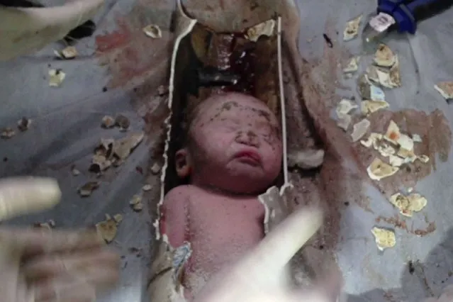 This frame grab taken from AFPTV footage received on May 28, 2013 shows rescue workers breaking away bits of a pipe to remove a newborn baby boy stuck inside in the city of Jinhua, in the eastern province of Zhejiang. (Photo by AFP Photo)