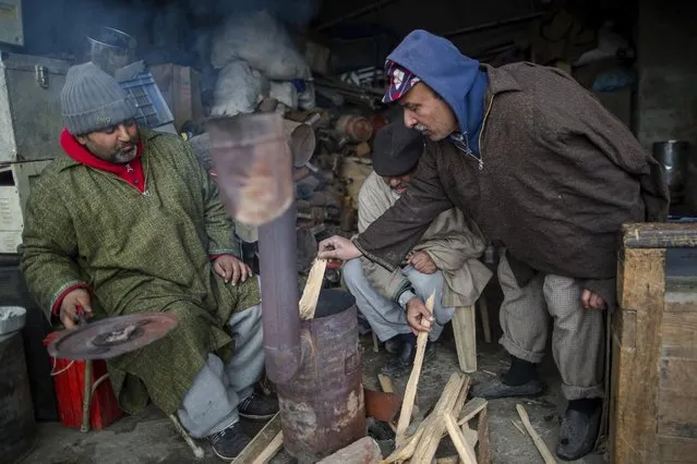 Kashmiri men warm themselves near a heater inside a shop in Srinagar, Indian controlled Kashmir, Thursday, January 19, 2017. A cold wave continues to grip Kashmir valley due to heavy snowfall. The only all weather road link that connects the Kashmir valley to the rest of India was opened Thursday after remaining closed for three consecutive days due to heavy snowfall. (Photo by Dar Yasin/AP Photo)