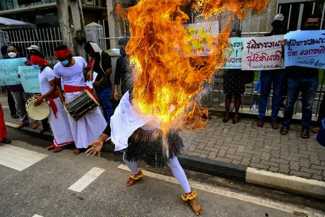 A performer accompanying teachers perform a blowing flame stunt during a demonstration demanding higher pay outside the Open University of Sri Lanka (OUSL) in Colombo on November 5, 2021. (Photo by Ishara S. Kodikara/AFP Photo)
