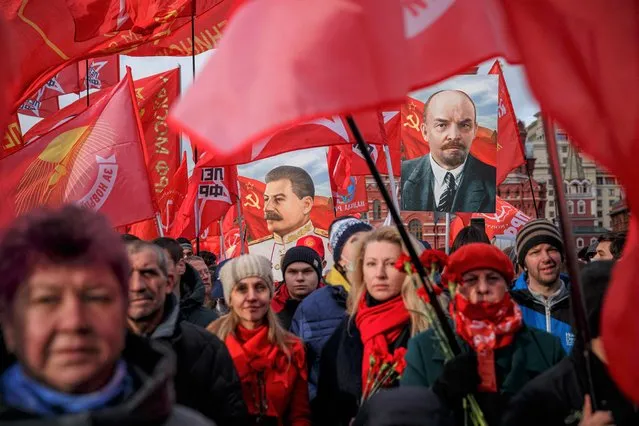 Russian Communist party activists and supporters carry portraits of Soviet founder Vladimir Lenin (R) and Soviet dictator Josef Stalin (L) as they attend a flowers-laying ceremony at the Lenin's Mausoleum on Red Square in downtown Moscow on November 7, 2021, marking the 104th anniversary of the Bolshevik Revolution also known as the October Revolution. (Photo by Dimitar Dilkoff/AFP Photo)