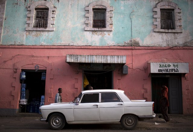 People walk past a Peugeot 404 in the old walled town of Harar in eastern Ethiopia, May 20, 2015. (Photo by Siegfried Modola/Reuters)