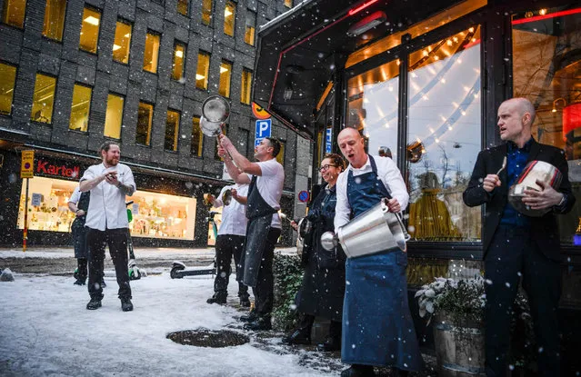 Restaurant owners and their staff make noise to protest against restrictions due to the corona (Covid-19) pandemic, outside a restaurant in central Stockholm, Sweden, on January 14, 2021. Serving alcohol at restaurants after 8 pm is not allowed until January 25, and a maximum of four guests are allowed to sit together. (Photo by Carl-Olof Zimmerman/TT News Agency/AFP Photo)