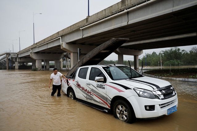 Resident Huang Jingrong cleans up his car with a boat tied up on the back, following heavy rainfall at a village in Qingyuan, Guangdong province, China on April 22, 2024. (Photo by Tingshu Wang/Reuters)