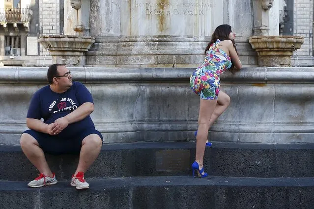 A woman poses for a photographer (not pictured) as a man sits next to her in downtown Catania, Italy April 20, 2016. (Photo by Tony Gentile/Reuters)