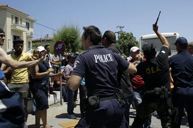 Police and coast guard scuffle with Syrians during a protest by refugees and migrants, demanding better living conditions and faster processing of their asylum registrations at the port of Mytilene, on the northern Greek island of Lesvos on Wednesday, June 17, 2015. The Aegean island has borne the brunt of a huge influx of migrants from the Middle East, Asia and Africa crossing from Turkey to nearby Greek islands. More than 50,000 migrants have arrived in Greece so far this year. (AP Photo/Thanassis Stavrakis)