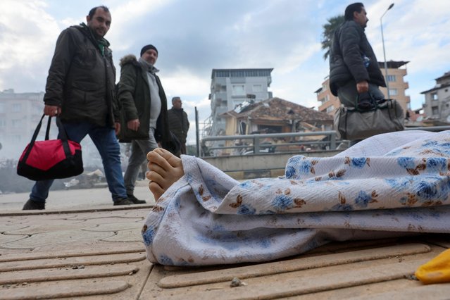 People look at a covered body, following an earthquake in Hatay Province, Turkey on February 7, 2023. (Photo by Umit Bektas/Reuters)