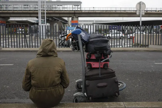 A passenger waits outside Orly airport, south of Paris, Saturday, March, 18, 2017. A man was shot to death Saturday after trying to seize the weapon of a soldier guarding Paris' Orly Airport, prompting a partial evacuation of the terminal, police said. (Photo by Kamil Zihnioglu/AP Photo)