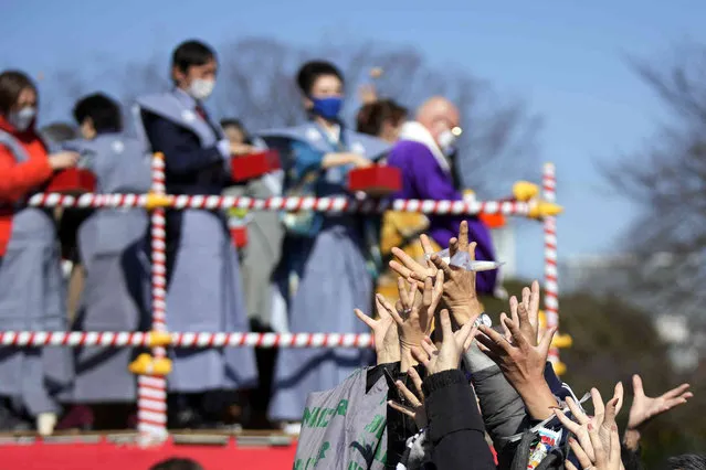 People try to catch lucky beans scattered by celebrities during the “Mame-maki”, a bean throwing ceremony, at the Zojoji Buddhist temple Thursday, February 3, 2022, in Tokyo. The ritual believed to bring good luck and drive away evil is performed annually to mark the beginning of the spring in the lunar calendar. (Photo by Eugene Hoshiko/AP Photo)