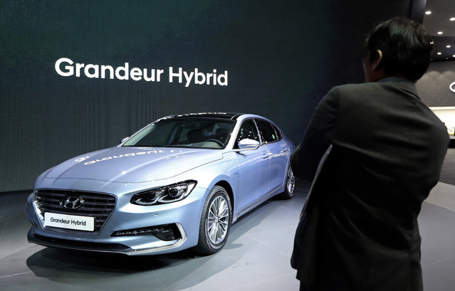 A man takes a photo of Hyundai Motor's Grandeur Hybrid vehicle during a media preview of the 2017 Seoul Motor Show in Goyang, South Korea, Thursday, March 30, 2017. (Photo by Lee Jin-man/AP Photo)