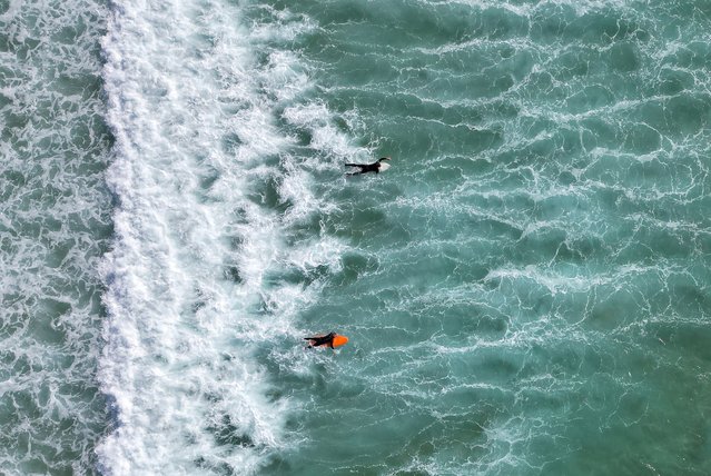 A drone view shows people surfing during spring sunshine, as the warm weather is set to continue into the weekend, at Fistral Beach, Newquay, south west Britain, on May 9, 2024. (Photo by Toby Melville/Reuters)