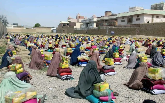 Afghan burqa clad women sit after they received ration aid in Kandahar, Afghanistan, 04 May 2016. Ummah welfare Islamic charity organization distributed tons of ration aid to Afghans who are currently experiencing a food crisis despite a good grain harvest last year. (Photo by Muhammad Sadiq/EPA)