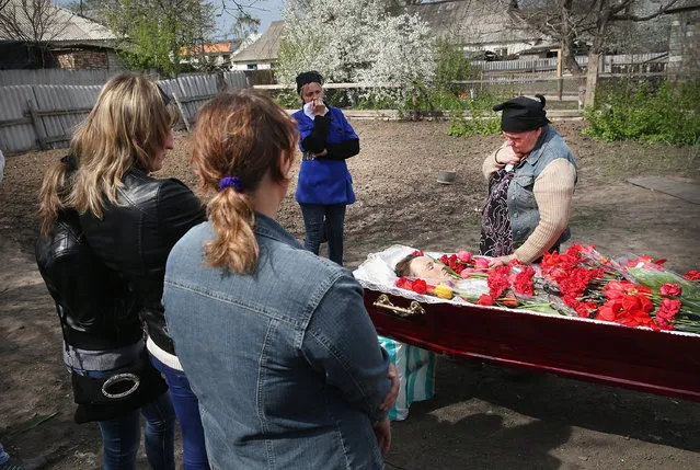 Family and friends mourn the death of  24-year-old Sasha, a pro-Russian activist, as his body rests in a casket outside the family's home in the small village of Aleksandrovka on April 22, 2014 near Slovyansk Ukraine. Sasha was killed during an Easter Sunday attack on a roadside checkpoint where he was working. Pro-Russian militants have been manning roadblocks around Slovyansk and have taken control of government buildings in the city. (Photo by Scott Olson/Getty Images)