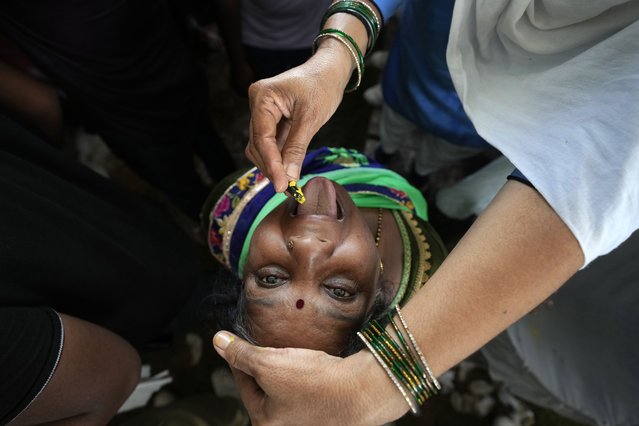 An asthma patient is administered a traditional “fish medicine” in Hyderabad, India, Saturday, June 8, 2024. Every year thousands of asthma patients arrive here to receive this fish therapy from the Bathini Goud family, which keeps a secret formula of herbs, handed down by generations only to family members. The herbs are inserted in the mouth of a live sardine, or murrel fish, and slipped into the patient's throat. (Photo by Mahesh Kumar A./AP Photo)