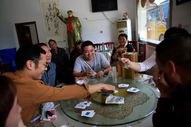 Chinese visitors play a card game in a restaurant where a Mao Zedong statue overlooks them in the background in Shaoshan, Hunan Province in central China, 28 April 2016. (Photo by How Hwee Young/EPA)