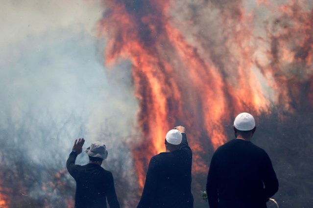 Local Druze men watch the flames burning a field after rockets launched from southern Lebanon landed on the Banias area in the Israel-annexed Golan Heights on June 9, 2024, amid ongoing cross-border clashes between Israeli troops and Hezbollah fighters. (Photo by Jalaa Marey/AFP Photo)