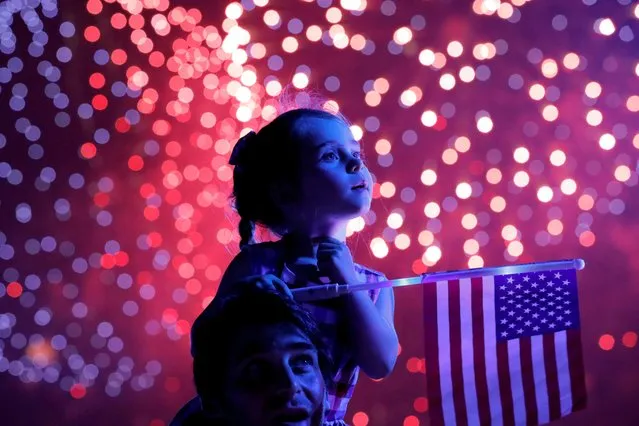 A child holds a U.S. flag as she watches the Macy's Fourth of July fireworks in New York City, New York, U.S., July 4, 2021. (Photo by Andrew Kelly/Reuters)