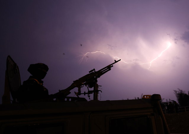 A Thai soldier with a heavy machine gun on a military vehicle guards as lightning strikes at the Second Thai-Myanmar Friendship Bridge in the Thai-Myanmar border Mae Sot district, Tak province, Thailand, 12 April 2024. Thai Foreign Affairs Minister Parnpree Bahiddha-Nukara on 12 April 2024 visits the Thai-Myanmar border town following clashes between Myanmar military and ethnic Karen rebels that forced Myanmar residents to escape the battle to Thailand. The Thai Foreign Minister Parnpree expresses his concern and hopes to seek an ASEAN consensus on the ongoing Myanmar armed conflicts. (Photo by Rungroj Yongrit/EPA)