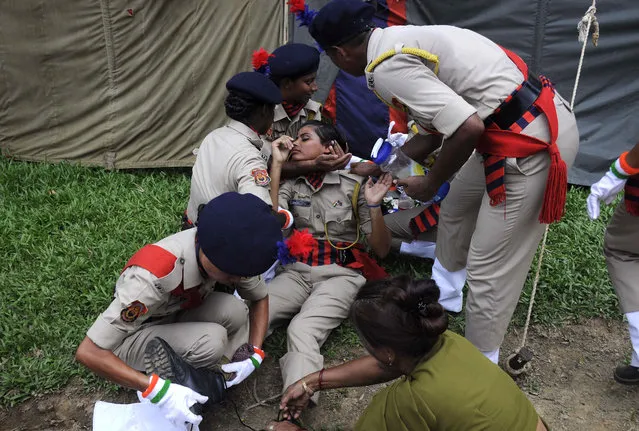 Indian police personnel assist a colleague after she fainted during a passing out ceremony at a police training academy in Agartala on May 11, 2017. 132 women police cadets passed out in the ceremony in the north- eastern state of Tripura. (Photo by Arindam Dey/AFP Photo)