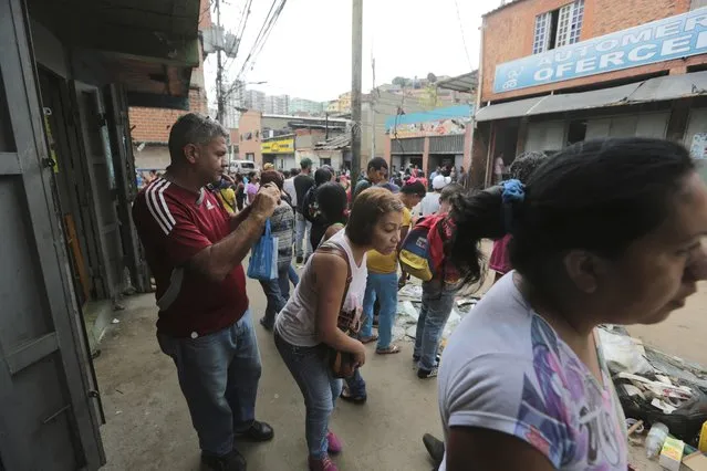Pedestrians look at shops looted the night before, in the El Valle neighborhood in Caracas, Venezuela, Friday, April 21, 2017. At least 12 people were killed overnight following looting and violence in Venezuela's capital amid a spiraling political crisis, authorities said Friday. Most of the deaths took place in El Valle, a working class neighborhood near Caracas' biggest military base where opposition leaders say a group of people were hit with an electrical current while trying to loot a bakery protected by an electric fence. (Photo by Fernando Llano/AP Photo)