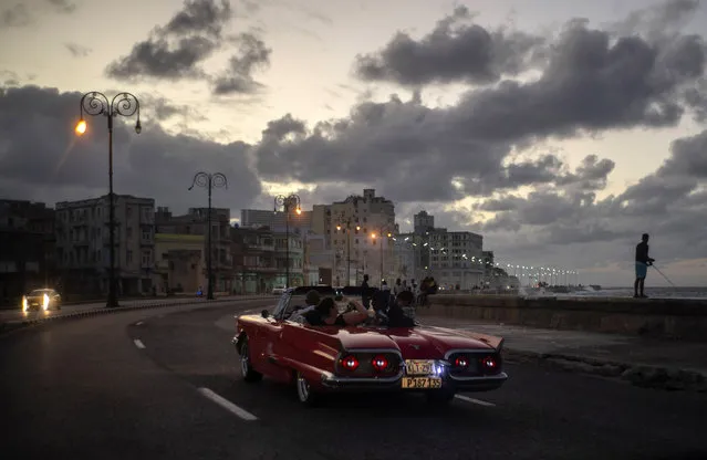 In this November 10, 2019 photo, tourists take a joy ride along the malecon sea wall in Havana, Cuba. (Photo by Ramon Espinosa/AP Photo)