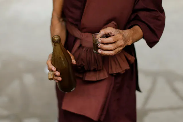 A Buddhist monk holds a glass with a vomit-inducing medication, before giving it to a rehabilitation patient at the detox area at Wat Thamkrabok monastery in Saraburi province, Thailand, February 3, 2017. (Photo by Jorge Silva/Reuters)