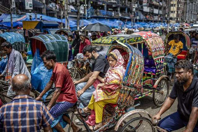 People ride a rickshaw along a street in Old Dhaka on August 17, 2024. (Photo by Luis Tato/AFP Photo)