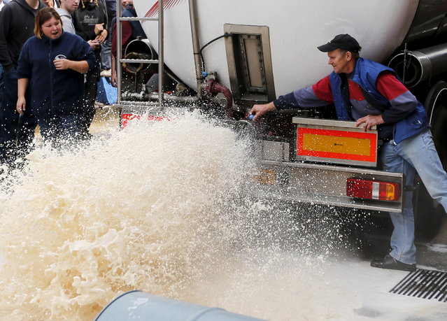 A Belgian dairy farmer pours milk from a truck during a protest against low milk prices at the milk processing factory Corman in Bethane near Liege, Belgium, July 30, 2015. (Photo by Francois Lenoir/Reuters)
