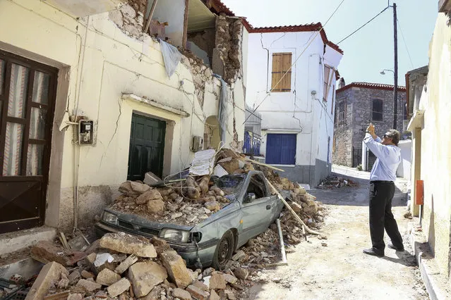 A man takes a picture of a damaged building caused by an earthquake in the village of Vrissa on the northeastern Greek island of Lesbos, Tuesday, June 13, 2017. Authorities in Greece have declared a state of emergency on the island of Lesbos after an earthquake that hit the island on Monday, June 12 and left one woman dead and more than 800 people displaced. (Photo by Manolis Lagoutaris/InTime News via AP Photo)