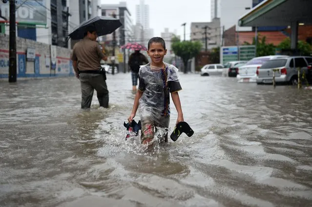 People walk in the flooded streets of Recife during the 2014 FIFA World Cup on June 26, 2014. (Photo by Patrik Stollarz/AFP Photo)