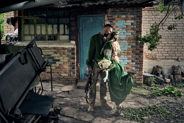 Volunteer military medics, code names Nikita and Polka, wearing national clothes, share a kiss during their wedding ceremony at their position on the frontline in the Donetsk region, Ukraine, Thursday, June 29, 2023. (Photo by Libkos/AP Photo)