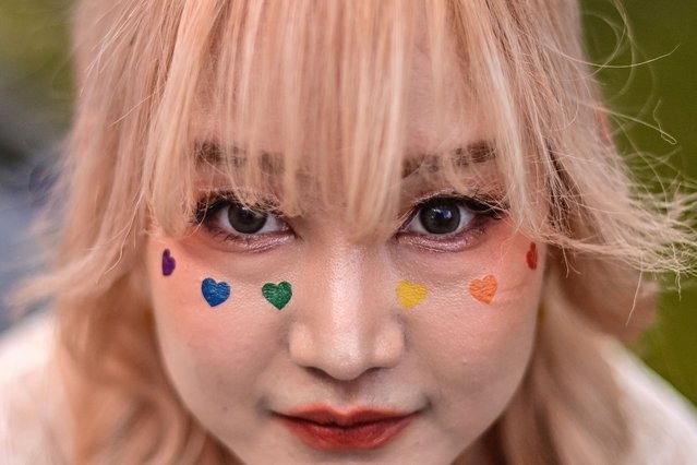 A member of the LGBTQIA+ community with rainbow-coloured hearts painted on her face, takes part in a pride march in Bangkok on June 4, 2023. (Photo by Manan Vatsyayana/AFP Photo)