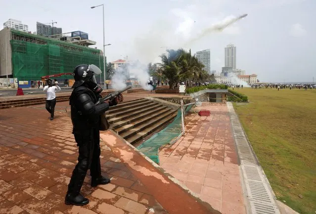 A riot police officer fires tear gas to chase back the supporters of Sri Lanka's ruling party during a clash with anti-government demonstrators, amid the country's economic crisis, in Colombo, Sri Lanka, May 9, 2022. (Photo by Dinuka Liyanawatte/Reuters)