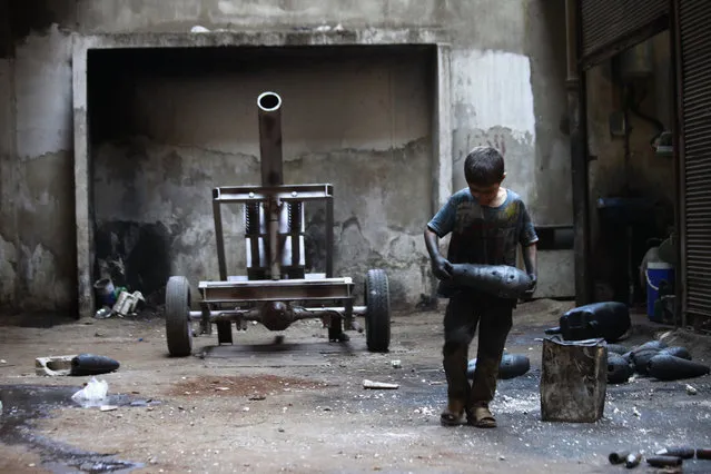 A young boy named Issa carries a mortar shell in a weapons factory of the Free Syrian Army in Aleppo, September 7, 2013. (Photo by Hamid Khatib/Reuters)