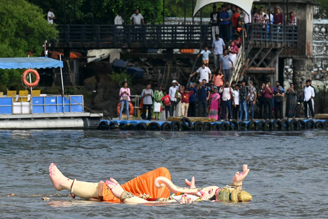 Ferry commuters watch as an idol of the elephant-headed Hindu deity Ganesha floats in the Arabian sea, after the culmination of the Ganesh Chaturthi festival in Mumbai on September 18, 2024. (Photo by Indranil Mukherjee/AFP Photo)