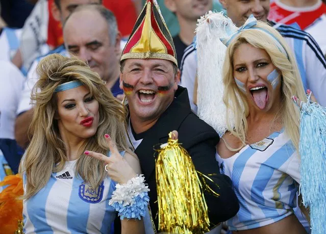 A Germany fan (C) reacts between fans of Argentina before the 2014 World Cup final between Germany and Argentina at the Maracana stadium in Rio de Janeiro July 13, 2014. (Photo by Kai Pfaffenbach/Reuters)