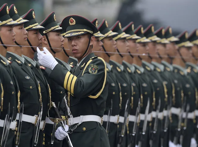 An officer of a Chinese People's Liberation Army honor guard uses a string to ensure members are standing in a straight line before a welcoming ceremony outside the Great Hall of the People in Beijing. (Photo by Kim Kyung-Hoon/Reuters)