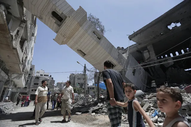 Palestinians inspect damage to adjacent houses from a fallen minaret of the Al-Sousi mosque that was destroyed in an Israel strike, at the Shati refugee camp, in the northern Gaza Strip, Wednesday, July 30, 2014. Israeli aircraft struck dozens of Gaza sites on Wednesday, including five mosques it said were being used by militants, while several other areas came under tank fire. (Photo by Lefteris Pitarakis/AP Photo)