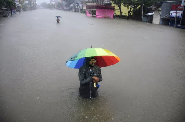 An Indian men wade while holding an umbrella through a flooded street during a heavy downpour in Agartala, the capital of northeastern state of Tripura on August 11, 2017. (Photo by Arindam Dey/AFP Photo)