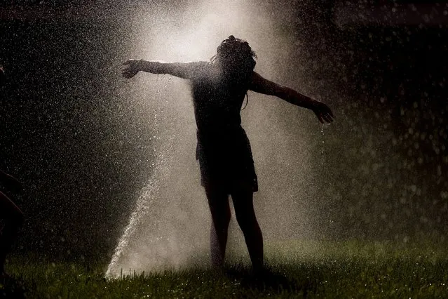 Ramona Allen, age 6, from Topeka, Kan., plays in a sprinkler on the grounds of the Kansas Statehouse Friday, June 24, 2022, in Topeka, Kan. (Photo by Charlie Riedel/AP Photo)