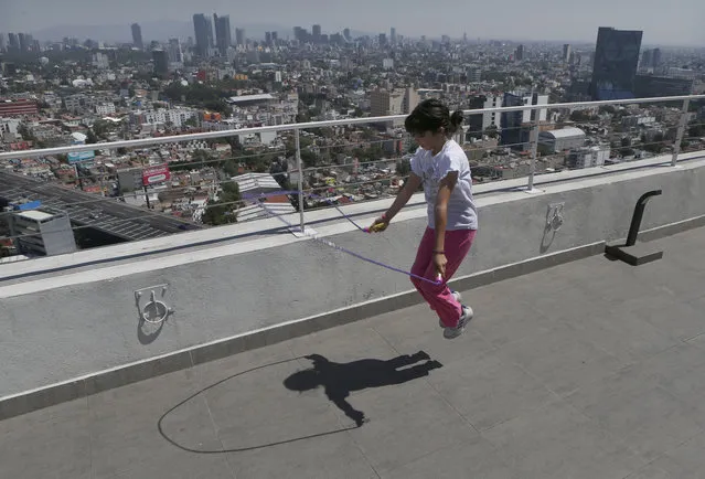 Staying home after her school canceled classes due to the spread of the new coronavirus, Sofia Cortes jumps rope on the roof of a building in Mexico City,Tuesday, March 31, 2020. Mexico's government has broadened its shutdown of “non essential activities,” and prohibited gatherings of more than 50 people as a way to help slow down the spread of COVID-19. The one-month emergency measures will be in effect from March 30 to April 30. (Photo by Marco Ugarte/AP Photo)