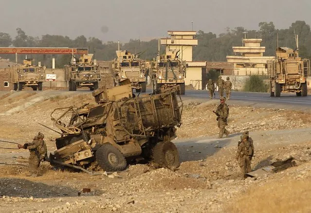 U.S. troops assess the damage to an armoured vehicle of NATO-led International Security Assistance force (ISAF) at the site of a suicide attack in Jalalabad province, August 24, 2014. At least six ISAF servicemen were wounded after a suicide car bomb attack on the ISAF convoy, Ahmad Zia Abdulzai, a spokesman for the provincial governor, said. (Photo by Reuters/Parwiz)