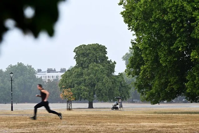 People walk during a heavy downpour on Clapham Common, following a long period of hot weather and little rainfall, in London, Britain on August 17, 2022. (Photo by Dylan Martinez/Reuters)