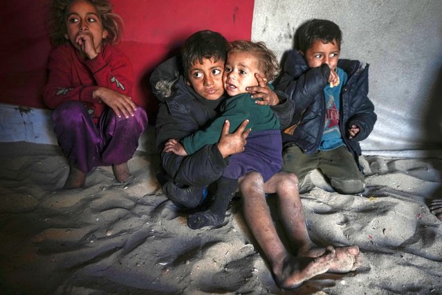 Palestinian Tamim Marouf, 6, sits inside his family's tent alongside his sister Hala, 10, and his brother Malek, 4, at a camp for internally displaced Palestinians on the beachfront in Deir al-Balah, central Gaza Strip, Friday, December 27, 2024. (Photo by Abdel Kareem Hana/AP Photo)