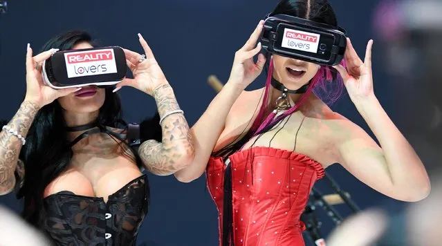 Two women use virtual reality p*rnography headsets at the Venus erotic trade fair in Berlin, Germany on 12 October 2017. (Photo by Alamy Live News)