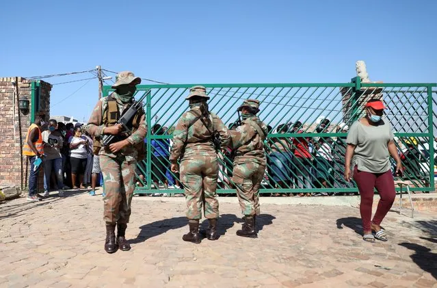 Military officers stand guard during food distribution, as South Africa starts to relax some aspects of a stringent nationwide coronavirus disease (COVID-19) lockdown, in Diepsloot near Johannesburg, South Africa, May 8, 2020. (Photo by Siphiwe Sibeko/Reuters)