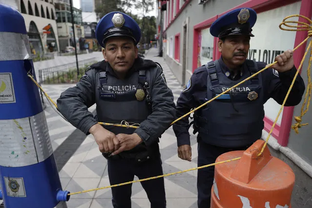 In this October 17, 2017 photo, police block access to a closed section of pedestrian Genova Street, where an 11-story building was heavily damaged in the Sept. 19 earthquake, in the Zona Rosa neighborhood of Mexico City. Local businesses are calling for quick demolition of the damaged building at Genova 33 and the reopening of the block to allow business to return to the busy commercial and tourist district. (Photo by Rebecca Blackwell/AP Photo)