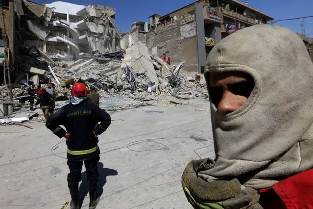 Firefighters remove debris to find bodies of people at the site of a collapsed building in Baghdad, Iraq on October 1, 2022. (Photo by Thaier Al-Sudani/Reuters)