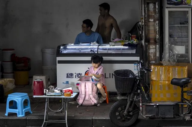 A girl writes homework in front of her parents store in Guangzhou, China, 22 June 2020. China races to contain a second wave of coronaviru​s cases mostly in Beijing. (Photo by Alex Plavevski/EPA/EFE)
