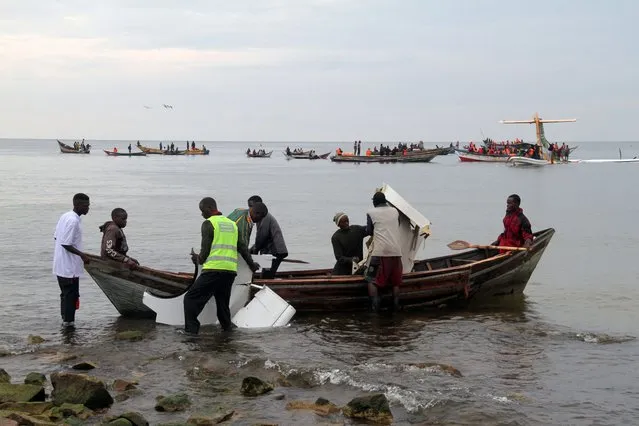 Rescuers carry debris as they search for survivors after a Precision Air flight that was carrying 43 people plunged into Lake Victoria as it attempted to land in the lakeside town of Bukoba, Tanzania on November 6, 2020. (Photo by Sitide Protase/AFP Photo)